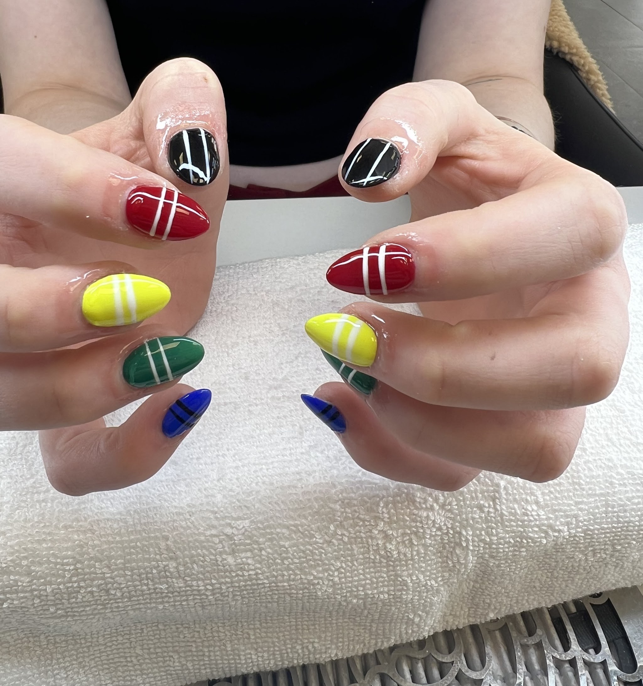 Gekleurde nagels in rood, geel, groen, blauw en zwart met witte strepen